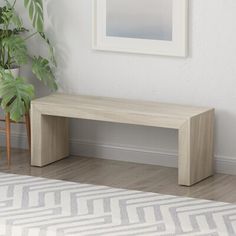 a wooden bench next to a potted plant in a room with white walls and wood flooring