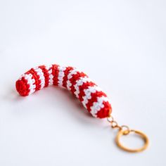 a red and white knitted keychain with a gold ring hanging from it