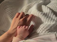 a person is laying down on a bed with their hand on the edge of her arm