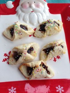 christmas pastries with chocolate and sprinkles on a white plate next to a santa clause