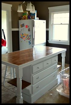 a kitchen island with two drawers in front of a refrigerator