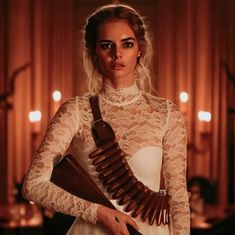 a woman holding a wooden instrument in her hands and wearing a white dress with lace on it