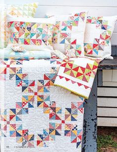 a quilted bed sitting on top of a wooden bench next to a white wall