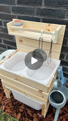 a wooden box filled with buckets and whisk in front of a brick wall