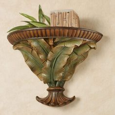 a wall mounted vase with leaves and a basket on the top, against a beige background