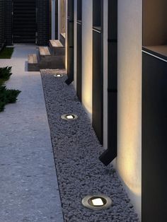 some lights that are on the side of a building near grass and bushes in front of it