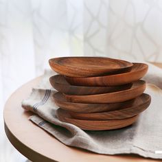 a stack of wooden plates sitting on top of a table next to a cloth covered napkin