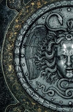 an ornate metal plaque with a woman's face in the center and two snakes around it