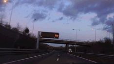 an image of a highway at dusk with clouds in the sky and street lights on either side