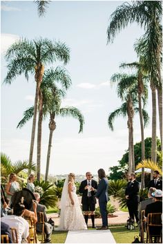 a bride and groom standing at the end of their wedding ceremony in front of palm trees