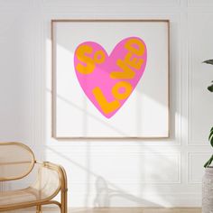 a pink heart with the word love spelled on it in yellow and pink, against a white wall