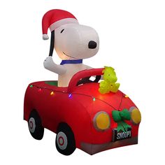 a large inflatable dog driving a red car with christmas lights on it's roof