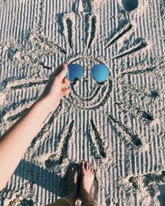 a person standing in the sand with their feet up and sunglasses on top of them