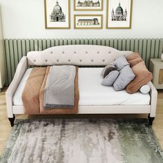 a bed with pillows and blankets on top of it in front of two framed pictures