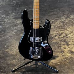 an electric bass guitar sitting on top of a tripod with its head resting on it's stand