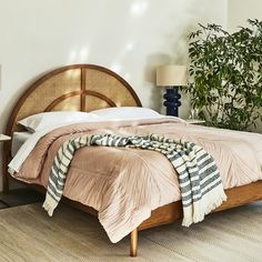 a bedroom with a bed, nightstands and plants in the corner next to it