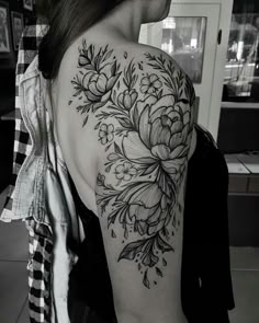 black and white photo of a woman's back shoulder with flowers on her left arm