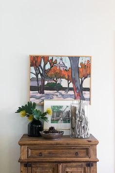 a wooden cabinet with vases and pictures on the wall