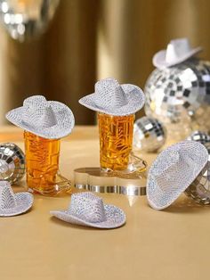 several glass items on a table with disco balls in the background and one has a white hat