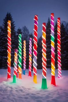 lighted poles in the snow at night with trees in the backgrounnd and lights on them