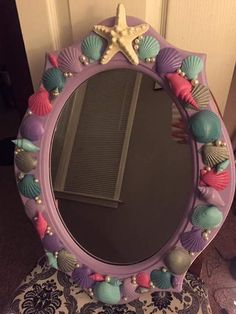 a mirror that is sitting on top of a chair with seashells around it