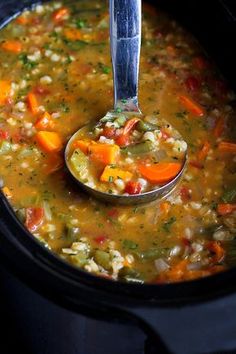 a spoon full of soup with carrots and celery in the slow cooker