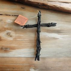 a cross made out of barbed wire with a note pinned to it on a piece of wood