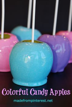 four candy apples with white and blue sticks sticking out of them, sitting on a table