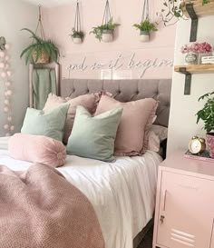 a bed with pink and green pillows on top of it next to a wall mounted planter