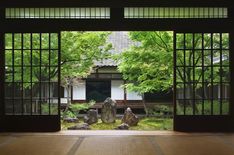 an open door leading to a garden with rocks and trees