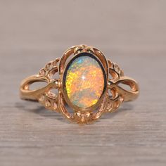 an opalite ring with filigrees and leaves on the sides, sitting on a wooden surface