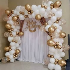 a white and gold balloon arch decorated with balloons