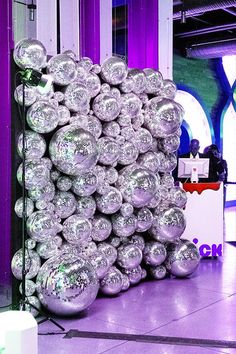 a large pile of shiny balls sitting on top of a floor next to a purple wall