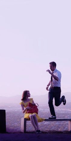 a man standing on top of a bench next to a woman