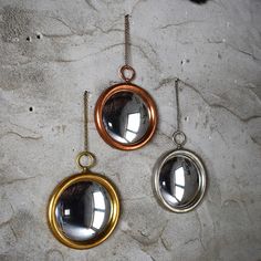 three mirrors hanging from chains on a wall