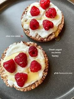 two desserts with raspberries and cream on top are sitting on a black plate