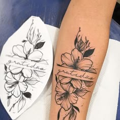 a woman's arm with flowers and a ribbon on it, next to a tattoo