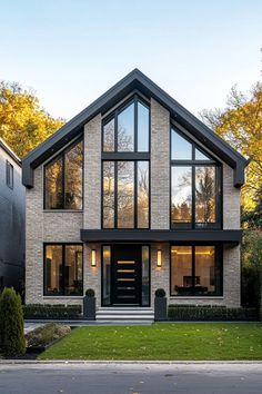 a modern house with large windows and black shutters on the front, surrounded by green grass