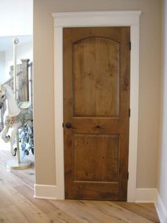 a wooden door is in the middle of a room with white walls and wood floors