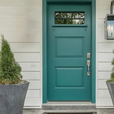 a blue door with two planters on the side of it and a light fixture