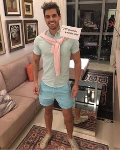 a man standing in front of a living room with a sign on his shirt and shorts