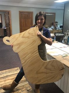 a woman holding up a wooden bear shaped object