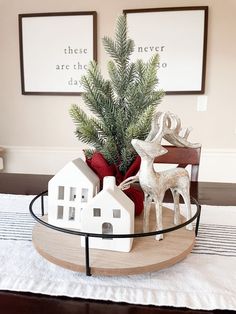 a small christmas tree in a glass bowl on a tray with houses and deer figurines