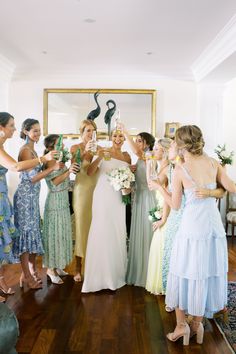 a group of women standing next to each other in front of a mirror holding champagne flutes