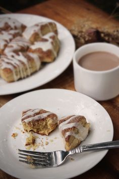 two white plates topped with pastries next to a cup of coffee