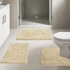 a bathroom with two rugs on the floor and a toilet in the shower stall