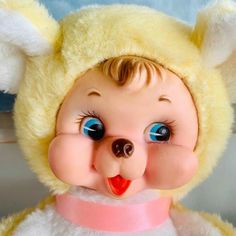 a close up of a stuffed animal with blue eyes and yellow fur on it's head