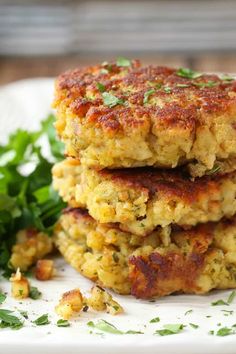 two crab cakes stacked on top of each other next to some green leafy greens