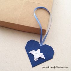 an origami heart shaped box with a blue ribbon hanging from it's side