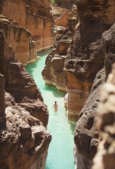 a person swimming in a river between two large rocks